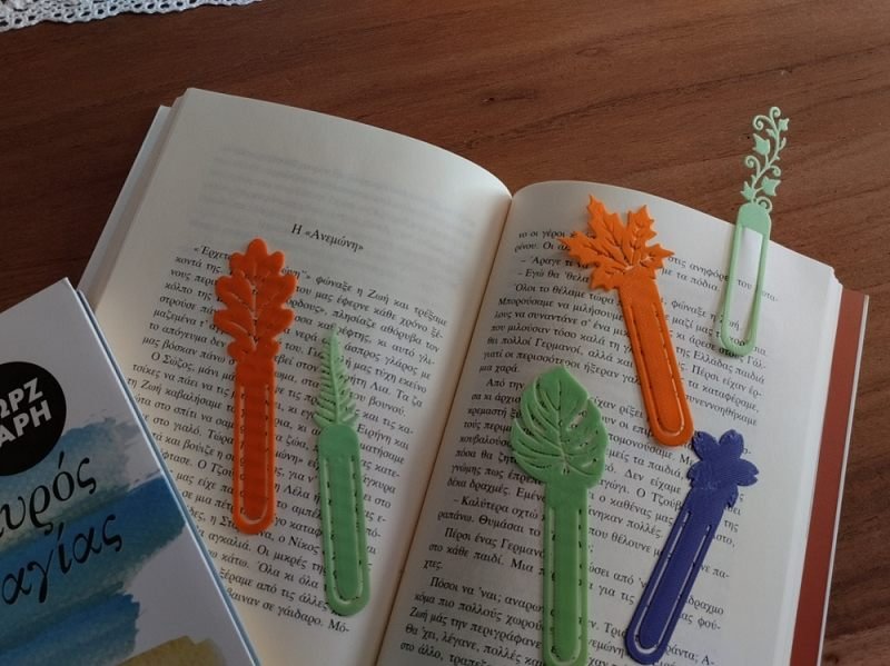 Gedruckte Lesezeichen in Blattformen und verschiedenen Farben auf einem aufgeschlagenen Buch